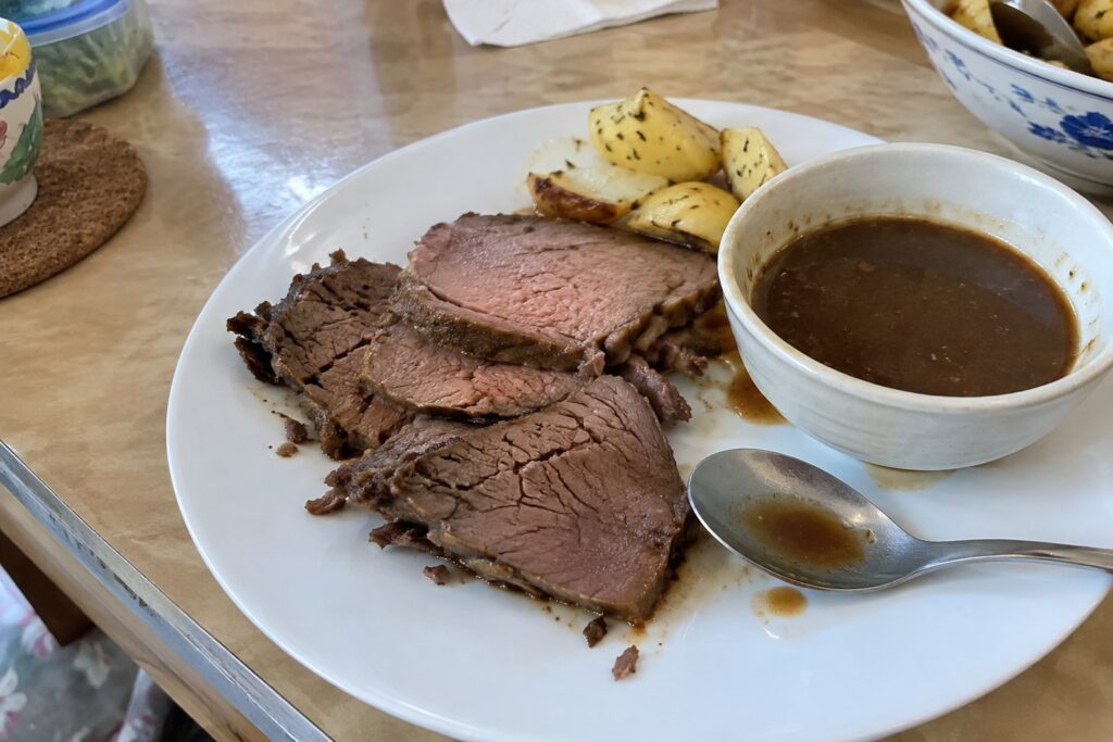Casual phone snapshot of sliced roast beef and gravy at a Singapore home dinner table