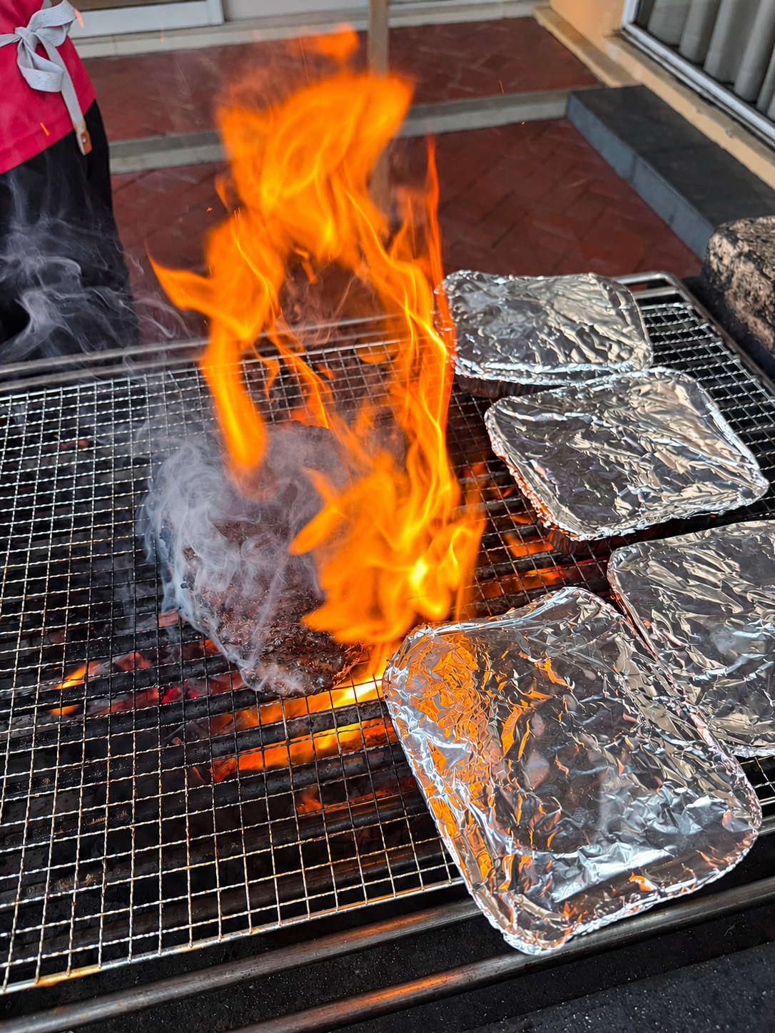 Charcoal flare-up at NSRCC bungalow BBQ with food trays on the grill