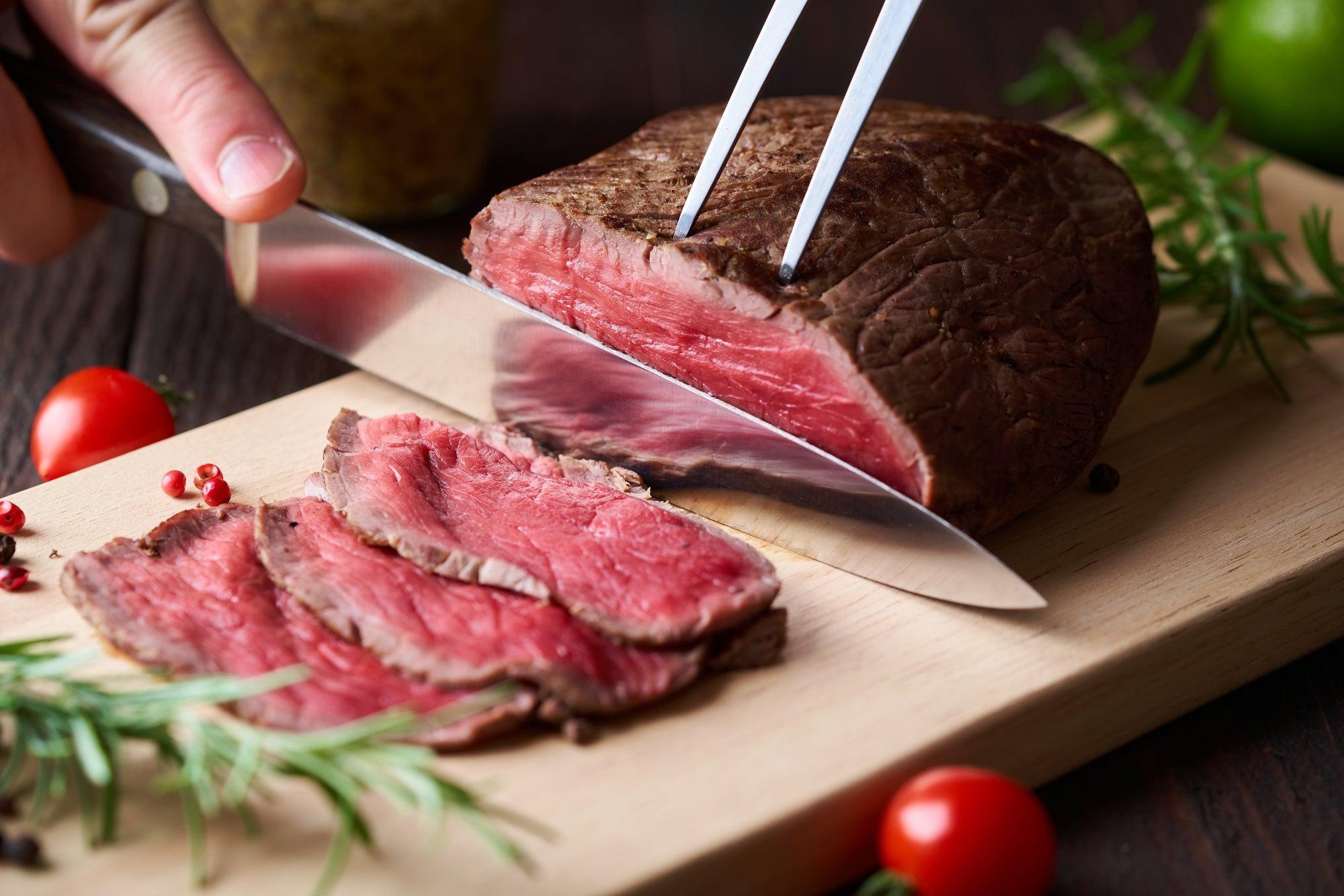 Steak grilling over charcoal with tongs