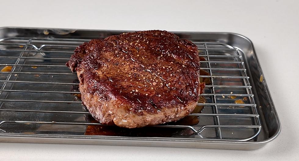 Cooked steak resting on a rack before carving